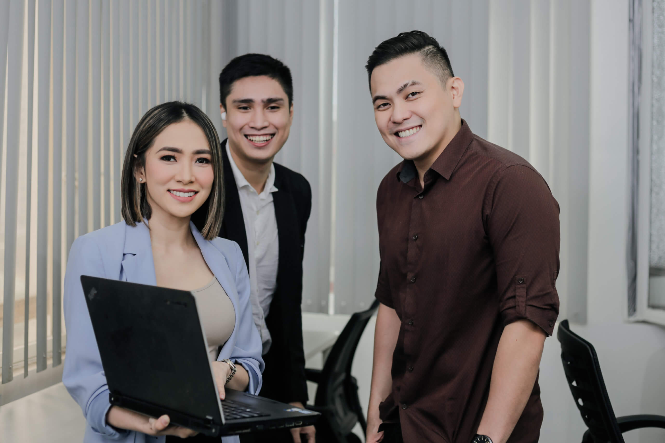 Three executives of a Chinese call center are smiling to the camera.