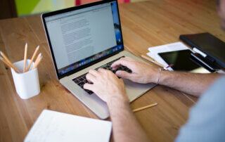 A man who provides content writing outsourcing services is working on his laptop.