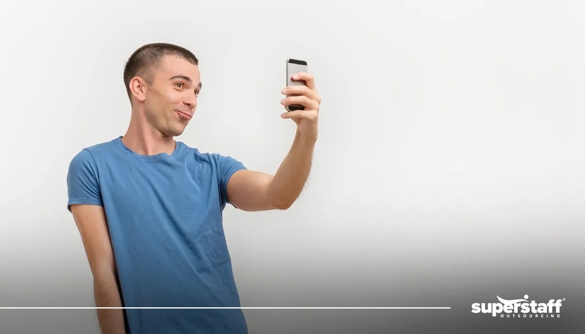 A photo shows a man coyly taking a selfie. 