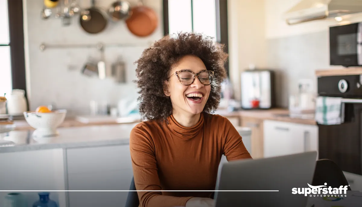 A girl smiles while working with a laptop. 