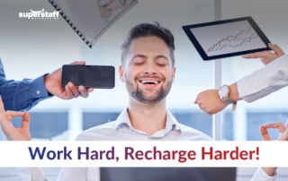 Maintaining Work-Life Balance in a Fast-Paced Environment: A professional smiling with eyes closed in a meditation pose while surrounded by work demands, symbolizing the importance of recharging amidst a busy schedule. The text overlay emphasizes 'Work Hard, Recharge Harder!' highlighting the need for balance in the workplace.
