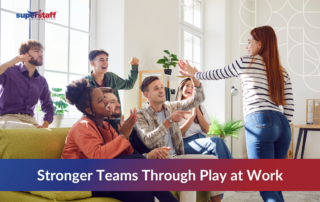 "A diverse group of young professionals engaging in a fun office game, laughing and cheering as a colleague participates. The setting is a bright, modern workplace with natural light and indoor plants, creating a relaxed and engaging atmosphere. The SuperStaff Outsourcing logo is in the upper left corner. The text overlay reads, 'Stronger Teams Through Play at Work,' emphasizing the benefits of gamifying work to enhance teamwork, motivation, and productivity in a BPO environment.