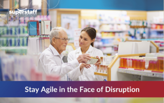 Pharmacist assisting elderly man in a pharmacy, symbolizing patient-centered innovations and agility in biotech industry trends.