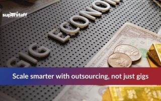 Close-up of the phrase 'Gig Economy' on a textured surface, surrounded by coins and gold bars, highlighting outsourcing.