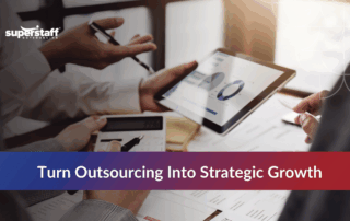 Team collaborating with a tablet and documents, focusing on outsourcing for strategic growth.